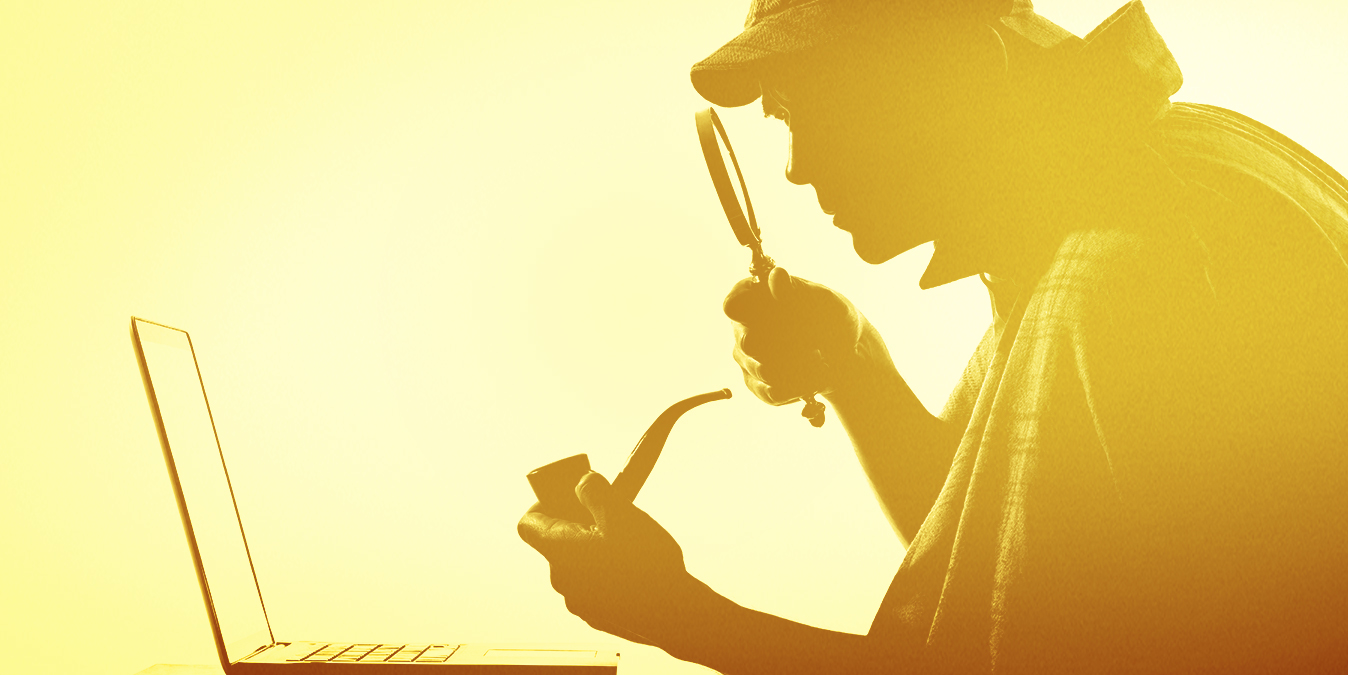 Man looking at a computer through a magnifying glass